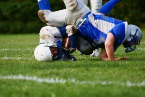 two football players colliding falling on the ground - sports injury concept